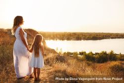 Woman and female child in summer dress enjoying the river view at dusk 47wgr4