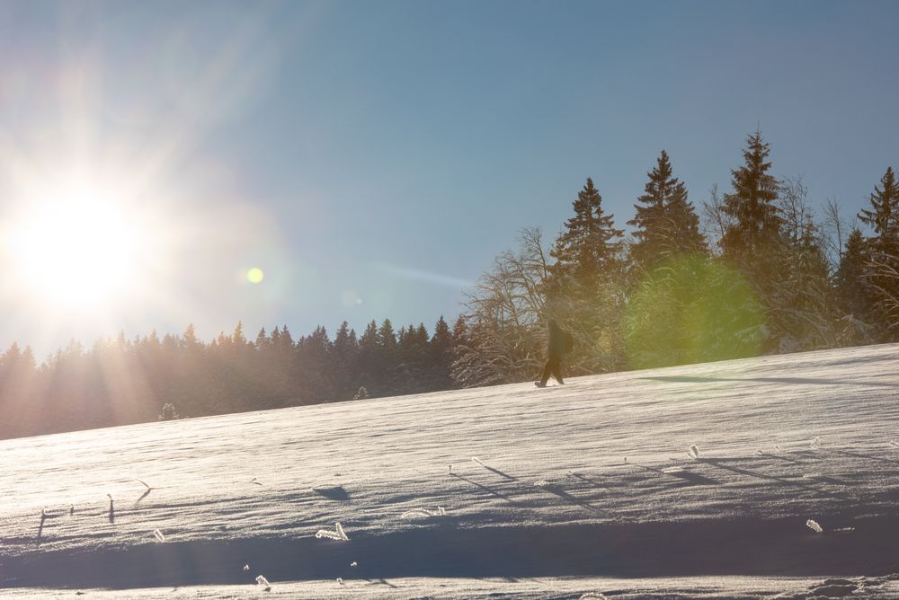 Man hiking through deep snow at sunrise in the  mountains