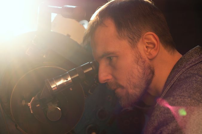 Man peers into telescope, focused on astronomical observation.