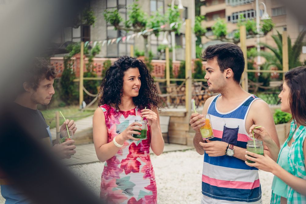 Friends having cocktails in garden as seen through fence