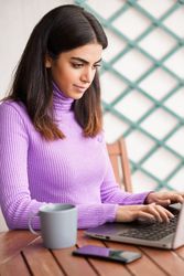 Female sitting on deck concentrating on computer, vertical
