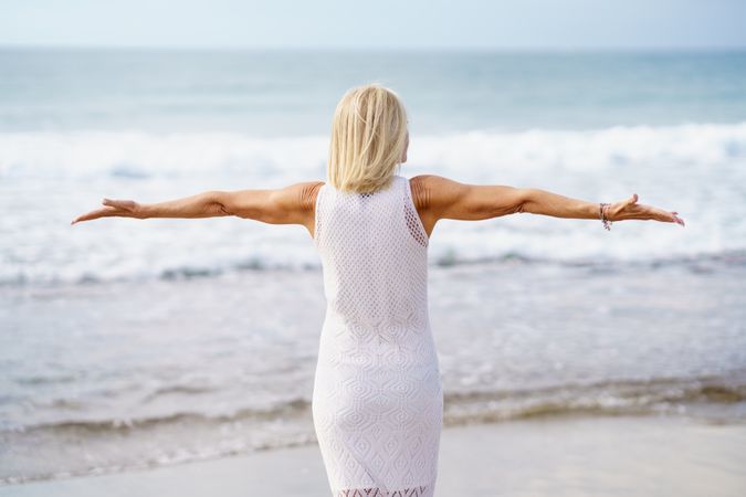Rear view of mature woman with outstretched arms on the coast