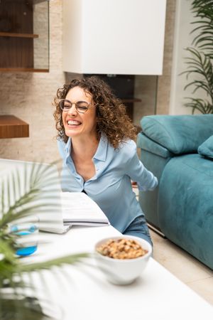 Smiling woman working from home on laptop in living room