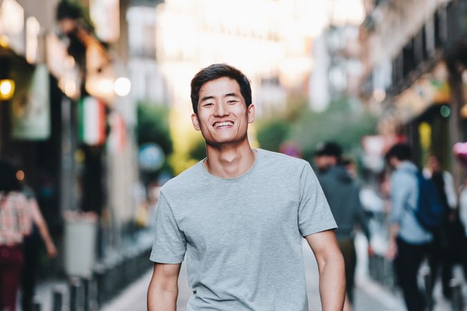 Confident Asian man walking along city street
