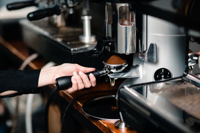Barista holding portafilter filling it with ground coffee for espresso shot