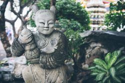Shabby statue near stones in garden