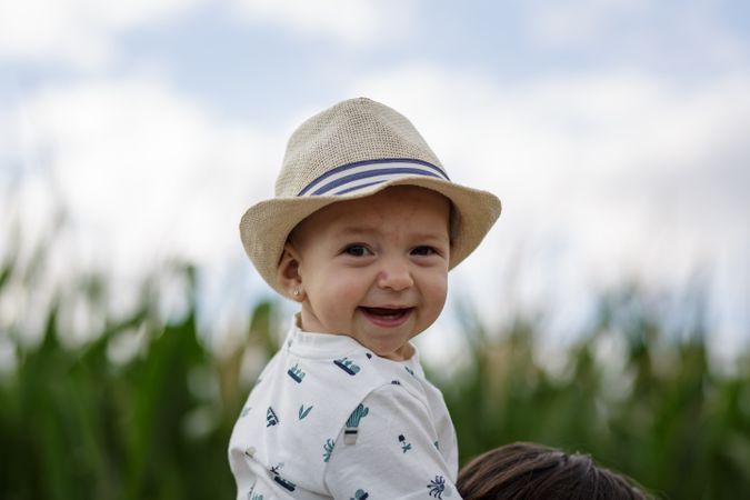 Stylish kid in hat smiling and looking at camera in field