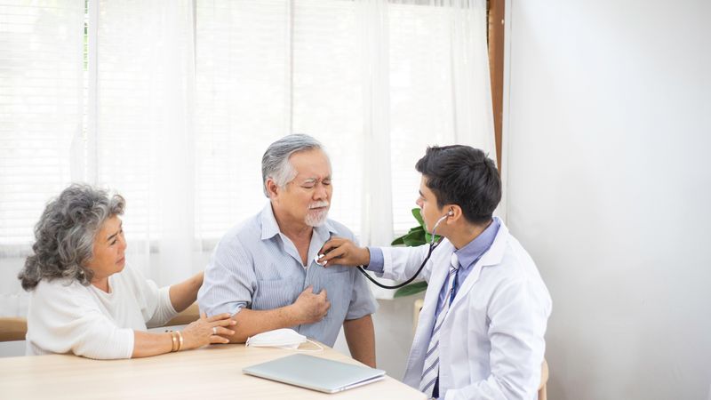 Doctor using stethoscope with older Asian patient