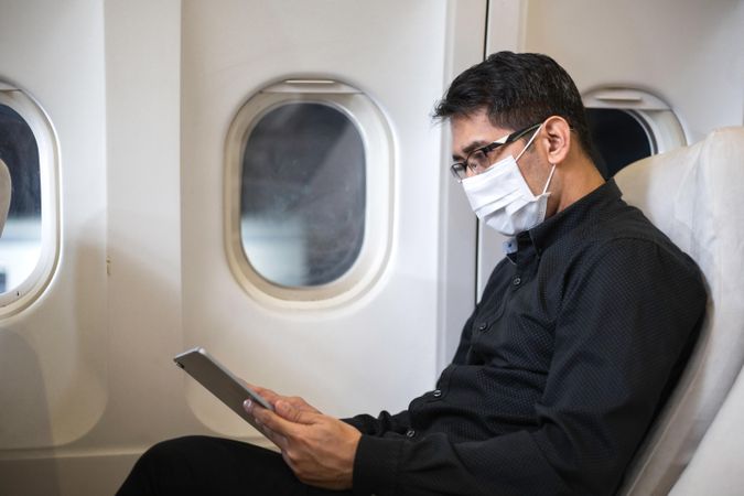 Businessman in suit checking digital tablet in airplane