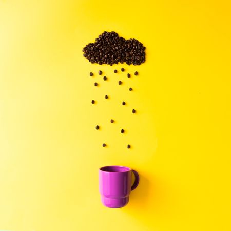 Coffee beans in shape of rainy cloud with purple cup on yellow background