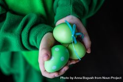 Hands holding green decorative eggs 0yXxO7