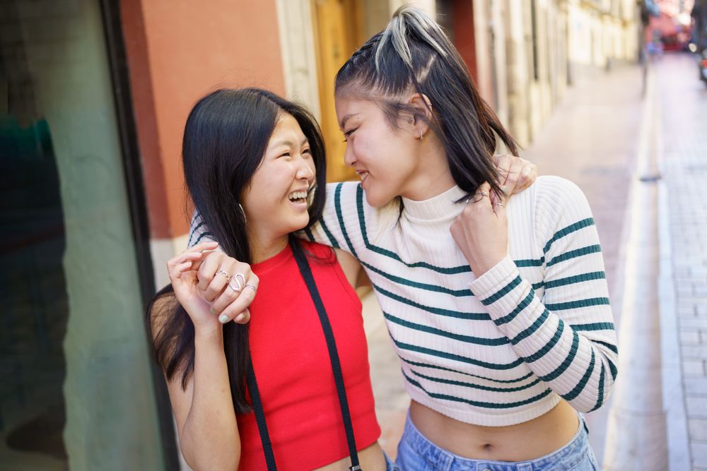 Two women smiling and walking down Spanish street