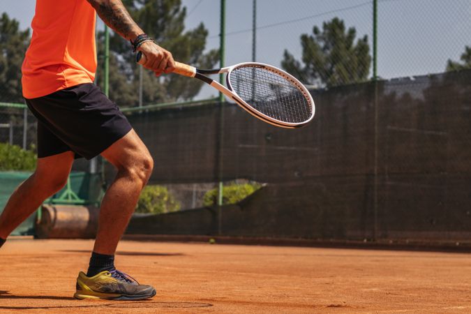 Man in sportswear playing tennis on a dirt tennis court