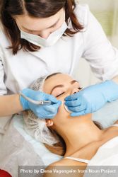 Woman having facial beauty treatment with machine on her forehead, vertical 5kopL5