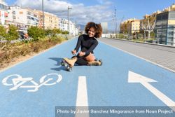 Smiling female in roller skates sitting in bike lane on sunny day 42wM7b