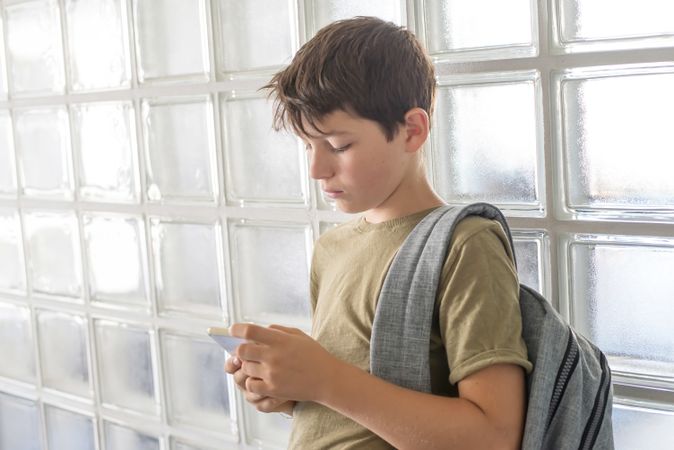 Sad teenager texting while leaning on wall