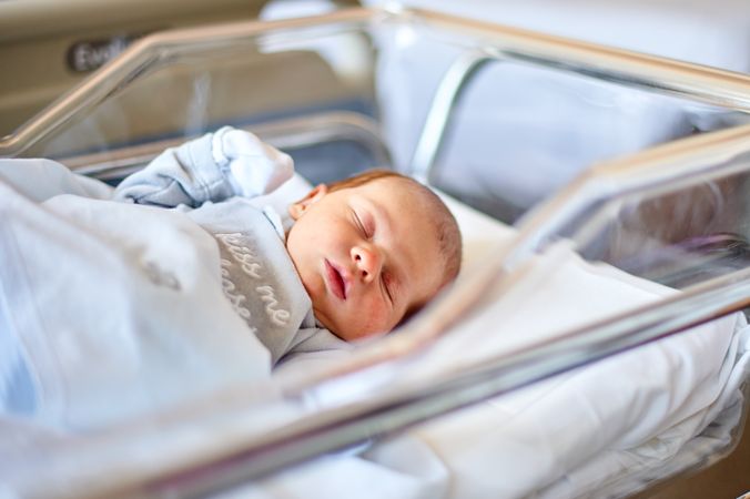 Newborn baby sleeping in its hospital crib