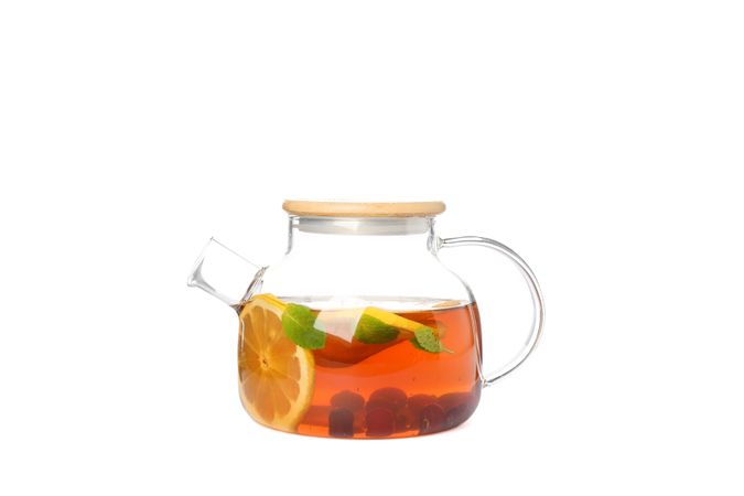 Glass teapot with lemon slices, mint and berries isolated on plain background