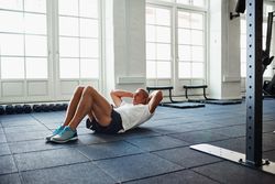 Man doing sit ups in bright gym