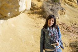 Female with camera standing in rocky and sandy terrain