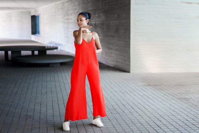 A Stylish Woman Dressed in a Bright Red Jumpsuit Gracefully Posing Outdoors in Daylight