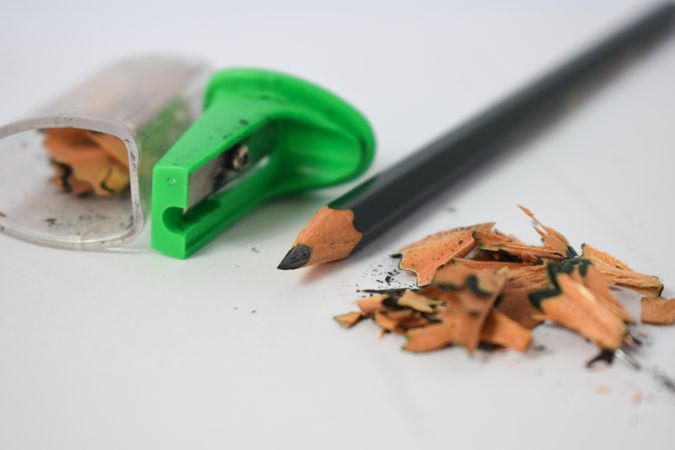 Sharpened pencil on table next to green sharpener with copy space