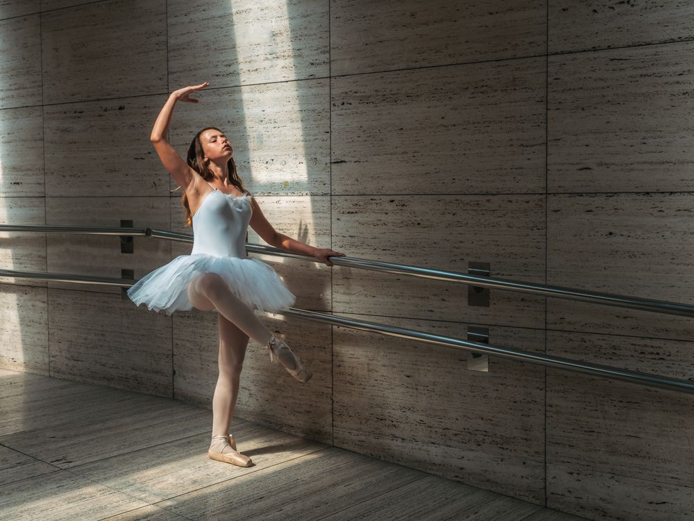 Ballerina doing ballet posing at rail in classroom