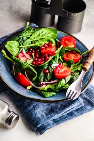 Fresh organic salad with spinach, tomato and pomegranate seeds