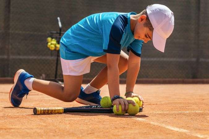 Little boy playing tennis on a dirt court