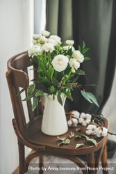 Spring buttercup flowers in enamel jug on chair 5R2EO5