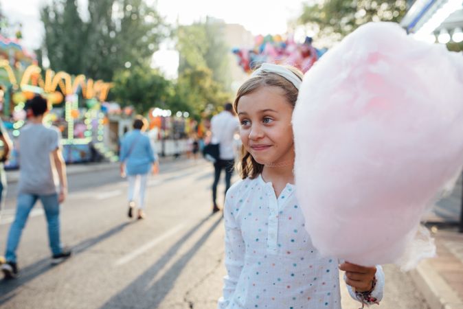 Cheerful girl eating cotton candy on street