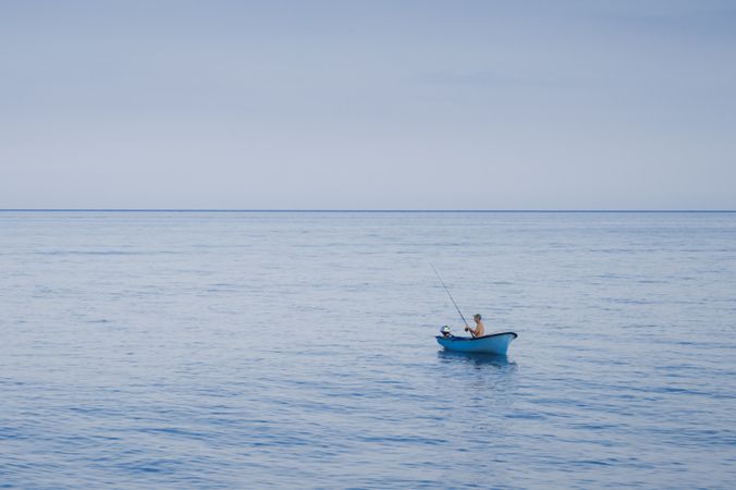Fisherman in blue boat on sea