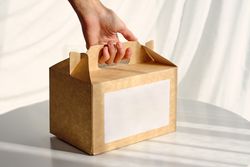 Woman taking carton box placed on table