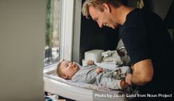Man on paternity leave caring for his baby on changing table 56ndj5