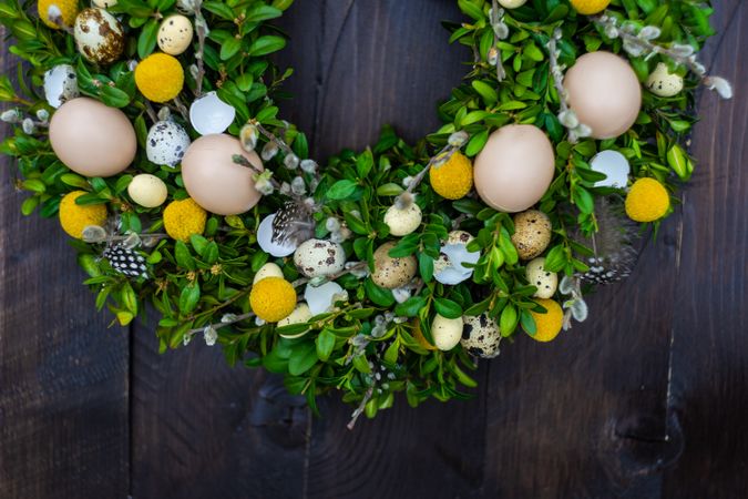 Eggs on decorative Easter wreath on wooden door