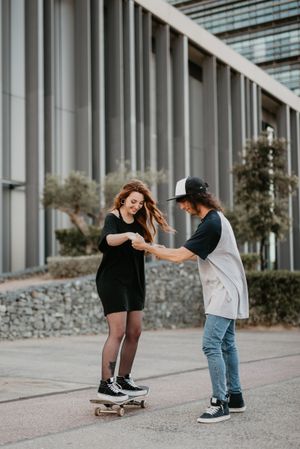 Man helping girlfriend to skate on road