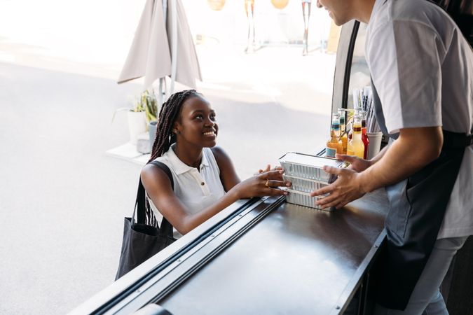 Happy female picking up packaged meals from food vendor