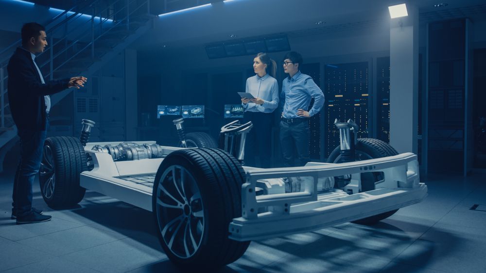 Automobile Design Engineers Talking while Working on Electric Car Chassis Prototype.