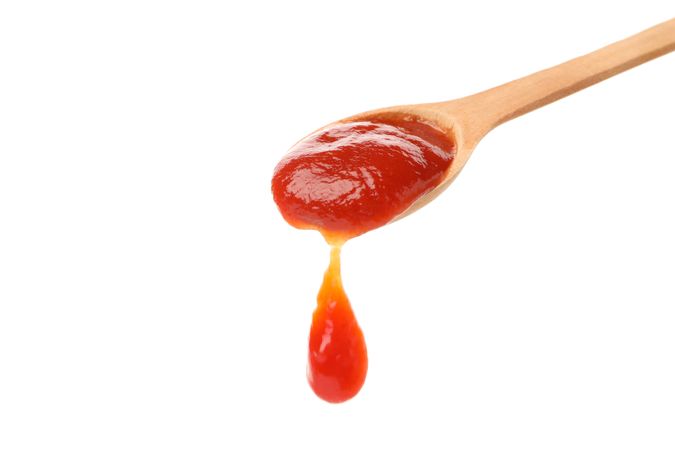 Wooden spoon with tomato sauce isolated on neutral background