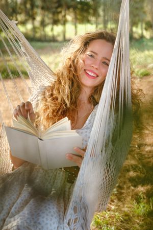 Delighted female enjoying reading on hammock