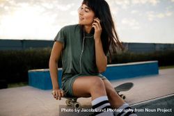 Woman relaxing at skate park listening music 0KOYz0