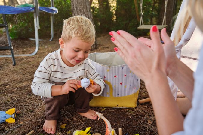 Mother applauding son playing with toy