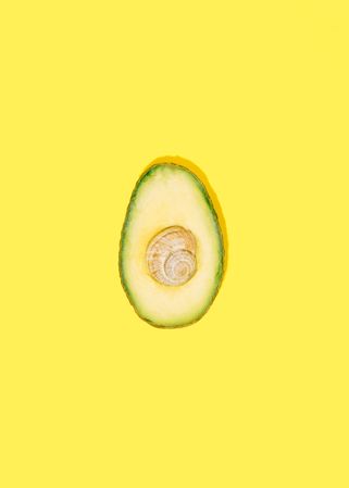 Flat lay of cut avocado on yellow background