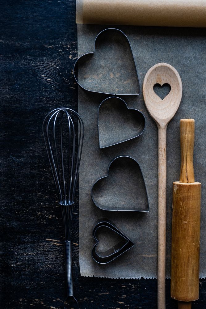 Top view of heart shaped cookie cutters and baking equipment on parchment paper
