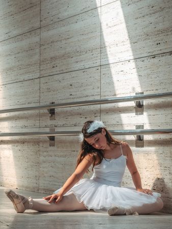 Ballerina sitting on floor stretching graceful leg
