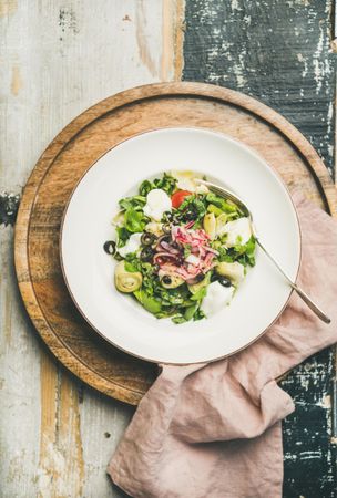 Top view of artichoke salad in bowl, on blue painted wooden background with linen napkin