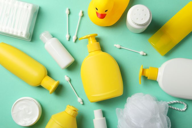 Baby hygiene accessories on mint background, top view
