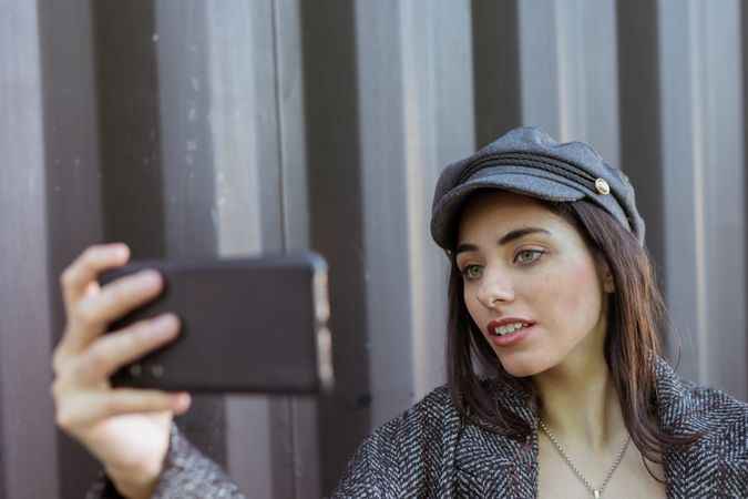 Charming Hispanic lady taking selfie near wall