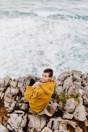Woman in yellow hoodie on stony shore