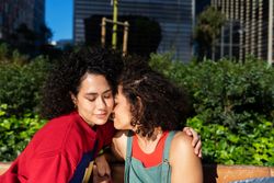 Happy female couple being affectionate in city park